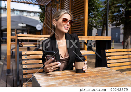 confident middle-aged woman drinking coffee in a cafe 99248879
