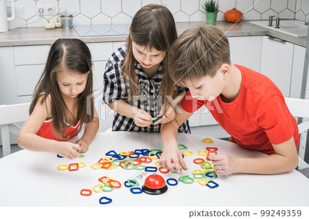 Funny school kids play toy constructor standing above kitchen table and looking down, from above view. Board game. Funny school kids play toy constructor standing above kitchen table and looking down, from above view. Board game. 99249359
