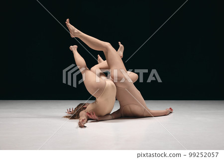 Two young girls, contemp dancers in bodysuits performing in experimental style over black background. Freedom of feelings 99252057