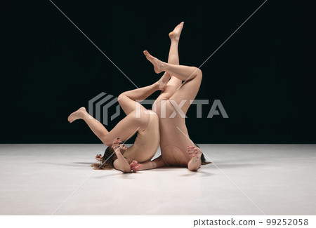Two young girls, contemp dancers in bodysuits performing in experimental style over black background. Freedom of feelings 99252058