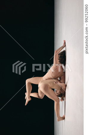 Two young girls, contemp dancers in bodysuits performing in experimental style over black background. Movements of feelings 99252060