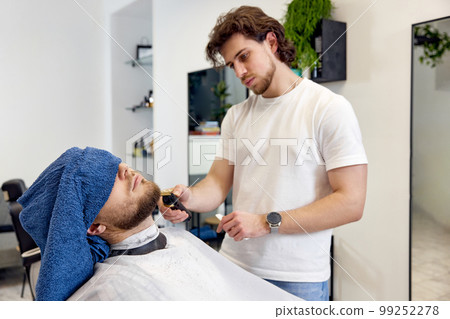 Barber shaving bearded man in barber shop. 99252278