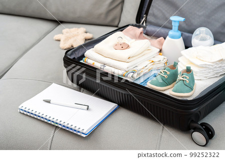 Open bag for maternity hospital. Suitcase of baby clothes prepared for newborn birth. Concept of getting ready for the maternity hospital, packing baby stuff Open bag for maternity hospital. Suitcase of baby clothes prepared for newborn birth. Concept of getting ready for the maternity hospital, packing baby stuff 99252322