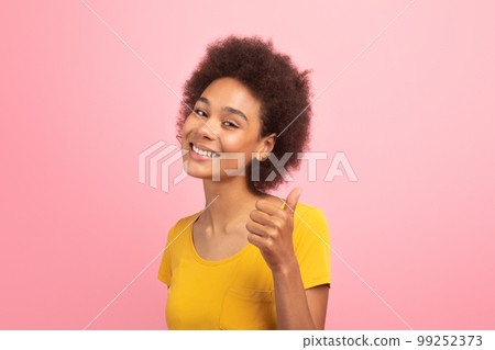 Smiling young black curly lady show thumb up, recommend and advice of ad and offer Smiling young black curly lady show thumb up, recommend and advice of ad and offer 99252373