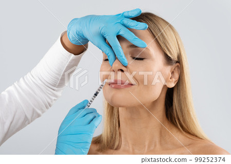 Middle aged woman gets cosmetic injection in nasolabial folds 99252374