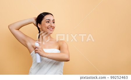 Portrait Of Smiling Young Indian Woman Using Deodorant Spray For Underarms Portrait Of Smiling Young Indian Woman Using Deodorant Spray For Underarms 99252463