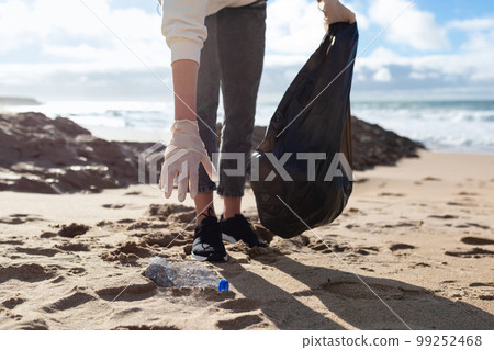 Young woman collecting plastic trash from the beach and putting it into plastic bag for recycle, closeup shot 99252468