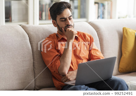Pensive young arab man working from home, looking for solution 99252491