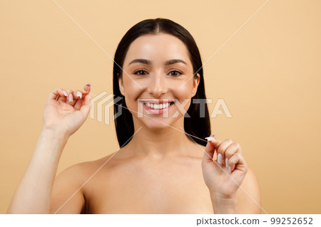 Beautiful Young Indian Woman Holding Dental Floss And Smiling At Camera Beautiful Young Indian Woman Holding Dental Floss And Smiling At Camera 99252652