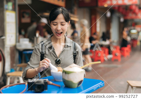 Happy young Asian woman backpack traveler enjoying street food at China town street food market in Bangkok, Thailand. Traveler checking out side streets. 99252727