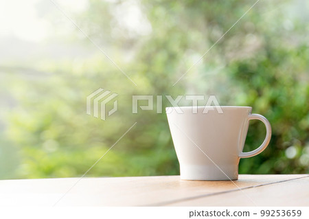 Cup with tea on table over mountains landscape with sunlight. Beauty nature background Cup with tea on table over mountains landscape with sunlight. Beauty nature background 99253659