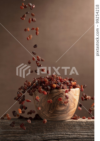 Raisins in a wooden bowl. 99254218