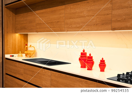 Modern brown wood oak kitchen cabinet equipment, granite black sink and glass gas stove in a home 99254535