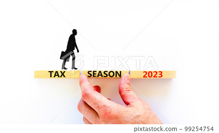 Tax season 2023 symbol. Concept words Tax season 2023 on wooden blocks on a beautiful white table white background. Businessman hand. Businessman icon. Business Tax season 2023 concept. Copy space. 99254754