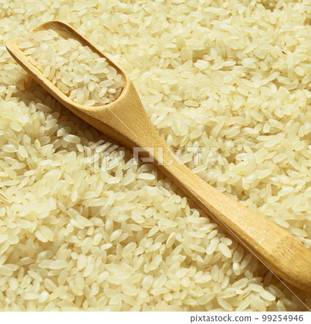 Fresh organic white raw rice grains texture and wooden spoon, uncooked rice background 99254946