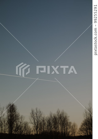airplane flies in sunset sky and leaving trail. Amazing panoramic sunrise or sunset sky. Gradient color. Sky texture, abstract nature background. 99255291