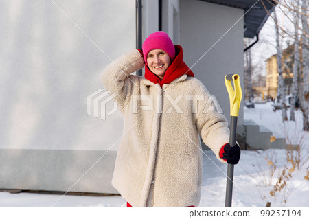 Portrait of a girl with a shovel in winter near the house Portrait of a girl with a shovel in winter near the house 99257194