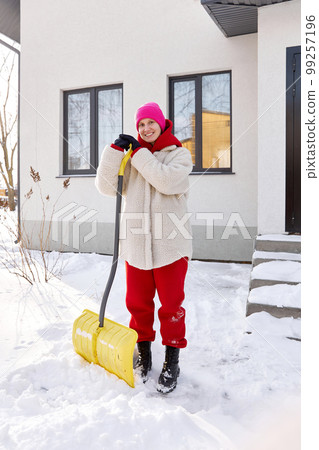 Portrait of a girl with a shovel in winter near the house Portrait of a girl with a shovel in winter near the house 99257196
