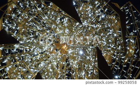 New Year and Christmas illumination of city streets. Flashing, flickering, shining, gleaming of electric bulbs and lights. Beautiful garlands and architectural forms. LED energy-saving garlands. Cone. 99258058