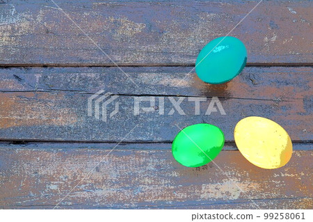 Multi-colored eggs painted with gouache and onion peel close up on wooden background. Three boiled eggs. Postcard poster for Easter. Easter holiday. Blue, yellow, green eggs Multi-colored eggs painted with gouache and onion peel close up on wooden background. Three boiled eggs. Postcard poster for Easter. Easter holiday. Blue, yellow, green eggs 99258061
