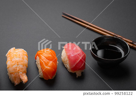 Traditional Japanese sushi top view with soy sauce and chopsticks on dark black minimal background. Sushi with salmon, tuna, shrimp, space for text 99258122