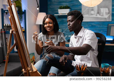 Art teacher showing new drawing technique to african american female student in home crafts studio. Young woman taking face to face pencil sketching classes at school of plastic arts. Art teacher showing new drawing technique to african american female student in home crafts studio. Young woman taking face to face pencil sketching classes at school of plastic arts. 99258288