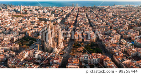 Aerial view of Barcelona City Skyline and Sagrada Familia Cathedral at sunset. Eixample residential famous urban grid. Cityscape with typical urban octagon blocks 99258444