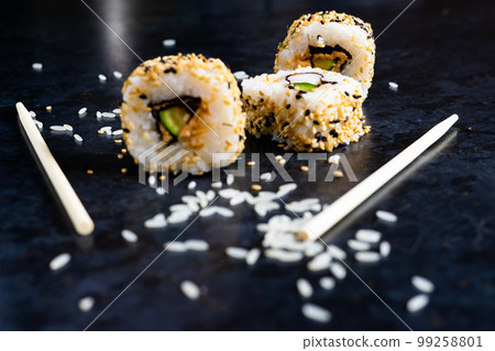 Sushi on a black table plate with wooden chopsticks. Eating japanese food at restaurant. 99258801