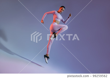 Attractive sporty woman in sportswear jumping on studio background. Sport and healthy lifestyle 99259562
