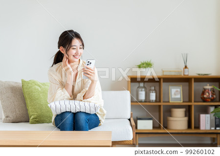 Young woman looking at her smartphone in the living room Young woman looking at her smartphone in the living room 99260102