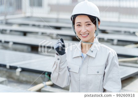 Portrait of a female worker standing in front of solar panels 99260918
