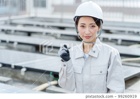 Portrait of a female worker standing in front of solar panels 99260919