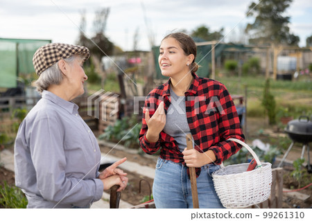 Female farmers friendly talking outside next to wooden fence on background with farm 99261310