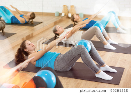 Girl doing crunches with bender ball in pilates studio 99261318