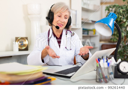 Female doctor in headphones with microphone consults patient on Internet 99261440