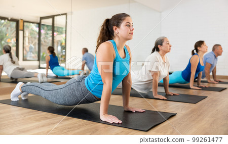 Girl performing back bending exercise during pilates group training Girl performing back bending exercise during pilates group training 99261477