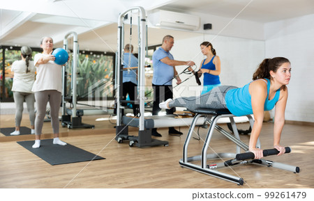 Young girl practicing pilates exercises on combo chair Young girl practicing pilates exercises on combo chair 99261479