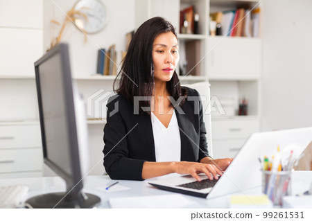 Smiling woman working with papers and laptop 99261531