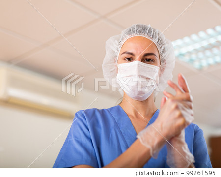 Nurse pulls gloves on her hands before the procedure 99261595