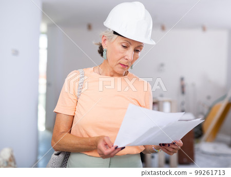 Mature woman with documents at renovating house Mature woman with documents at renovating house 99261713
