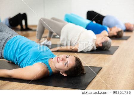 Smiling young girl performing glute bridge during workout Smiling young girl performing glute bridge during workout 99261726