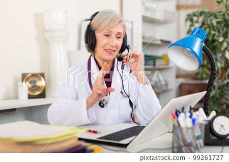 Female doctor in headphones with microphone consults patient on Internet Female doctor in headphones with microphone consults patient on Internet 99261727