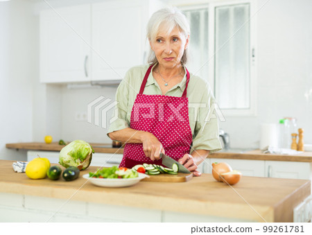 Mature woman cutting fresh vegetables for dinner 99261781