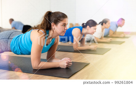 Group of young elderly people exercising Pilates while standing in plank on mats in rehabilitation center Group of young elderly people exercising Pilates while standing in plank on mats in rehabilitation center 99261804