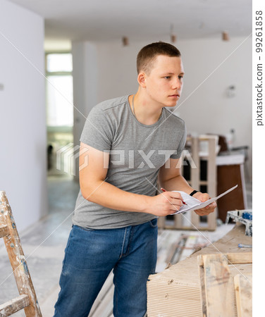 Fifteen-year-old worker fills out paperwork on a construction site indoors Fifteen-year-old worker fills out paperwork on a construction site indoors 99261858