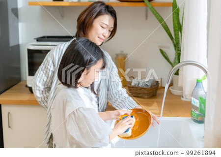 Girl helping with washing dishes Parent and child Girl helping with washing dishes Parent and child 99261894