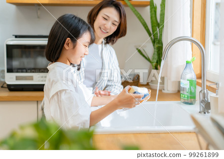 Girl helping with washing dishes Parent and child 99261899