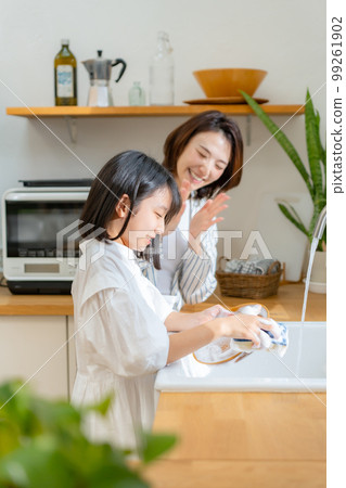 Girl helping with washing dishes Parent and child 99261902