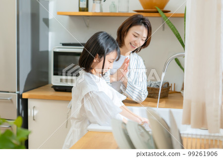 Girl helping with washing dishes Parent and child 99261906