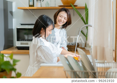 Girl helping with washing dishes Parent and child 99261910
